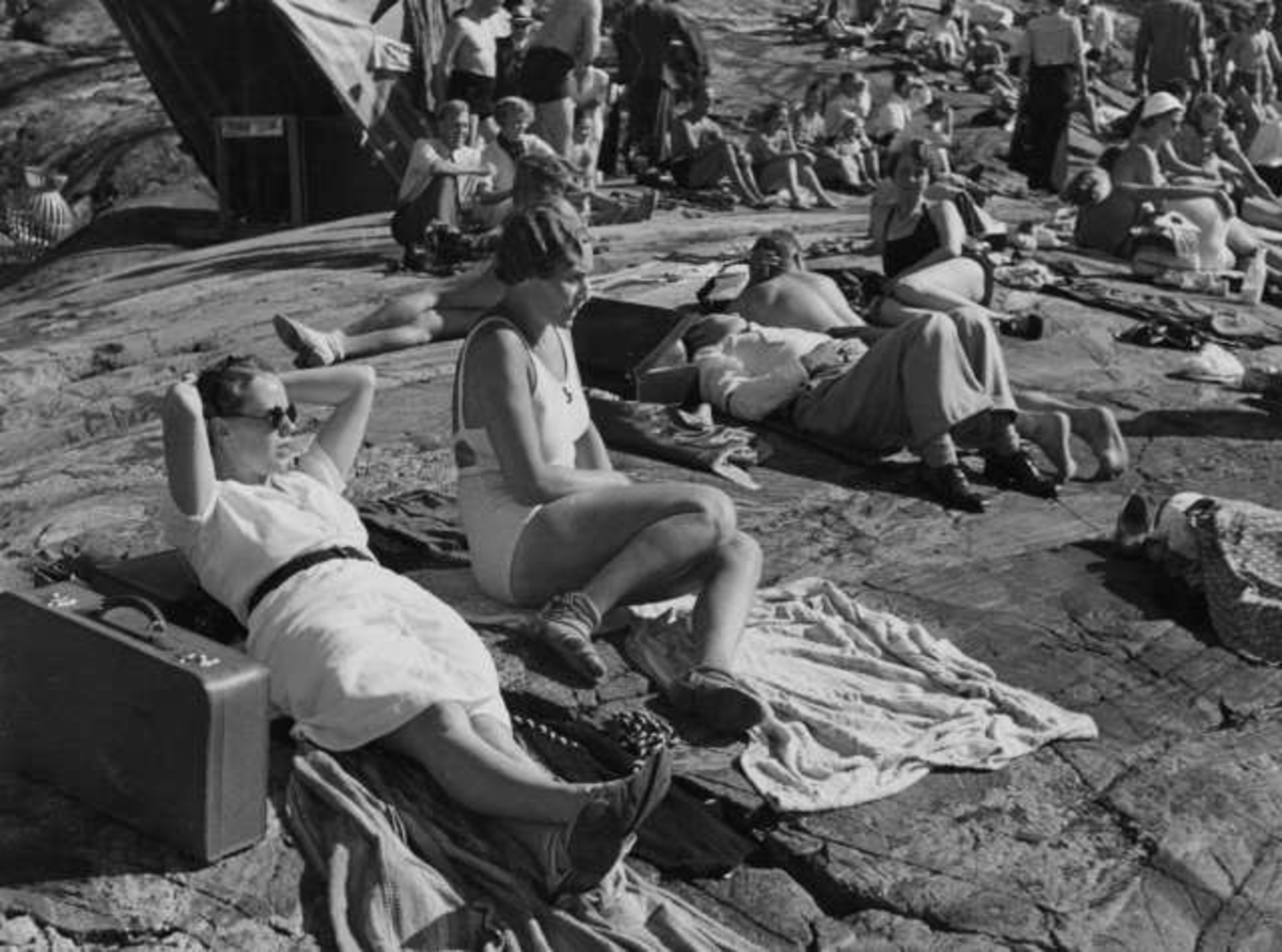 Strandliv med badegjester som soler seg på svaberget ved sjøen på Ingierstrand bad utenfor Oslo.