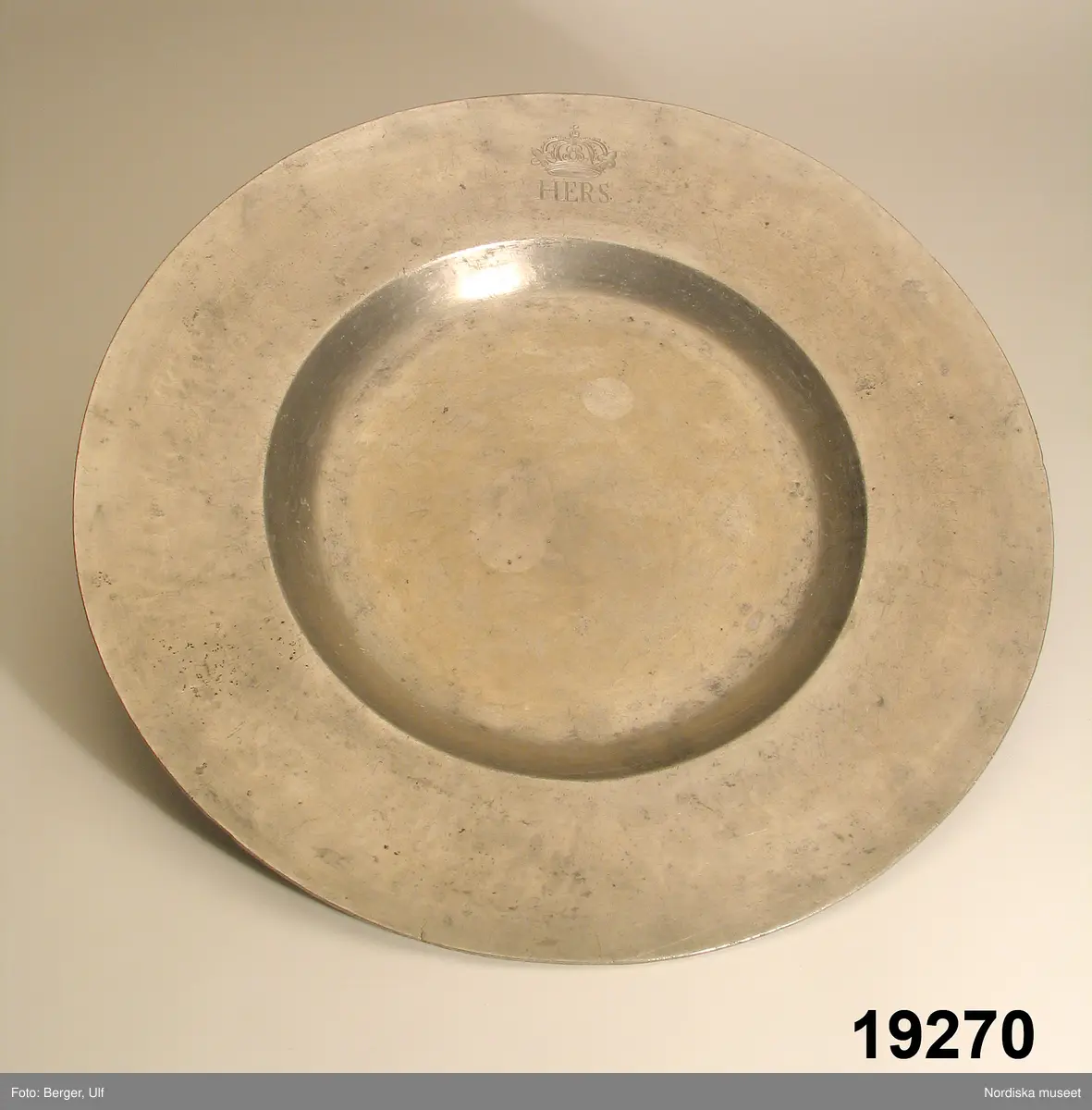 Katalogkort:
"TALLRIK
tenn
Rund, flat.
Monogram Krona HERS
På baks. Wastena 1670 nr 27."