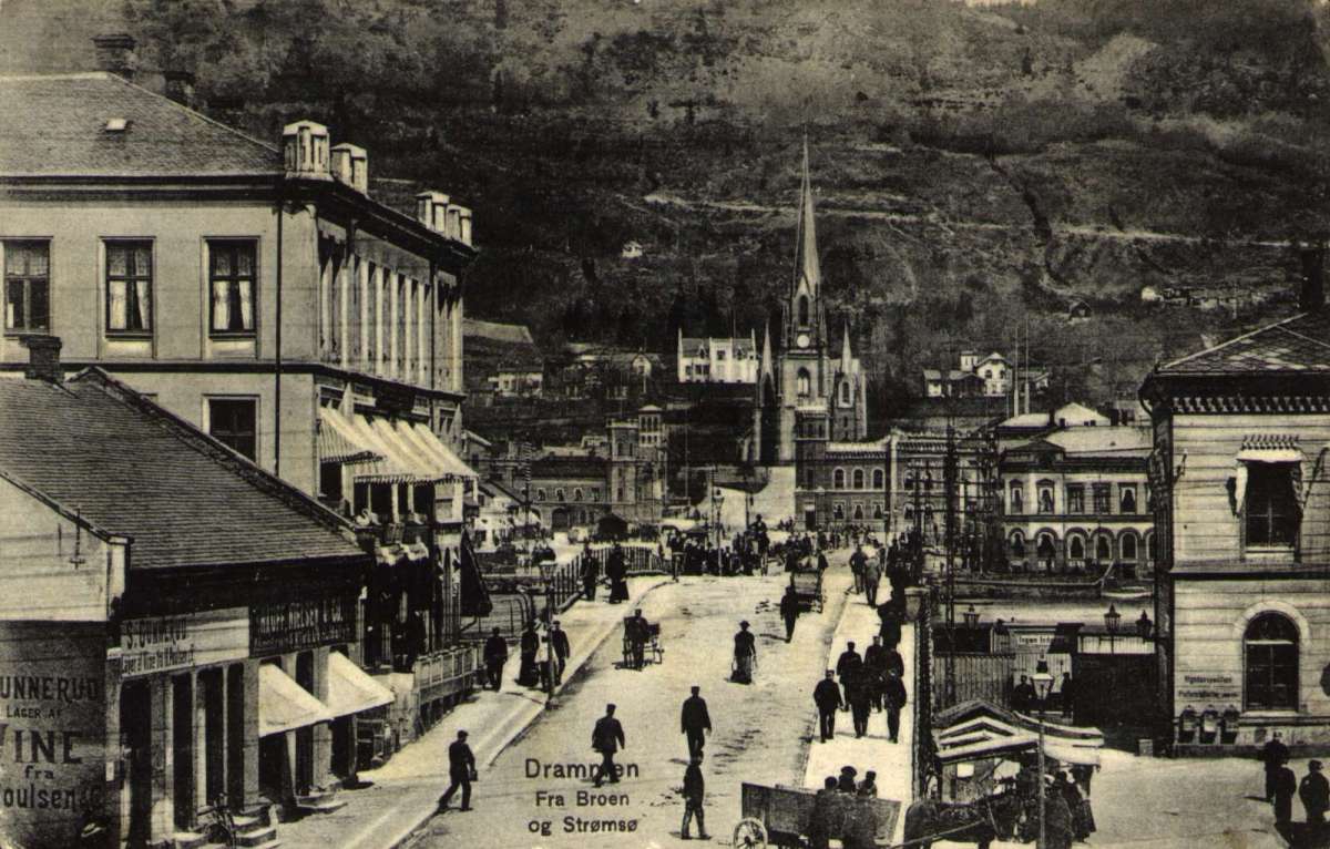 Postkort. Kirke ligger på den andre siden av broen. Mange mennesker rundt i byen. Stemplet 19.03.1907."Drammen. Fra Broen og Strømsø."