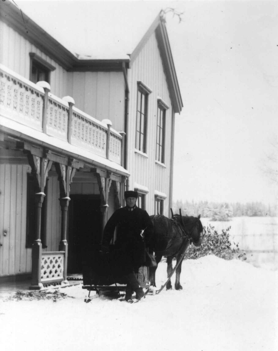 Dal gård, Ullensaker. Mann med hest og kjøretøy foran hovedbygningen vinterstid.
Fra serie fotografert av kammerherre Fredrik Emil Faye (1844-1903), gårdens eier.