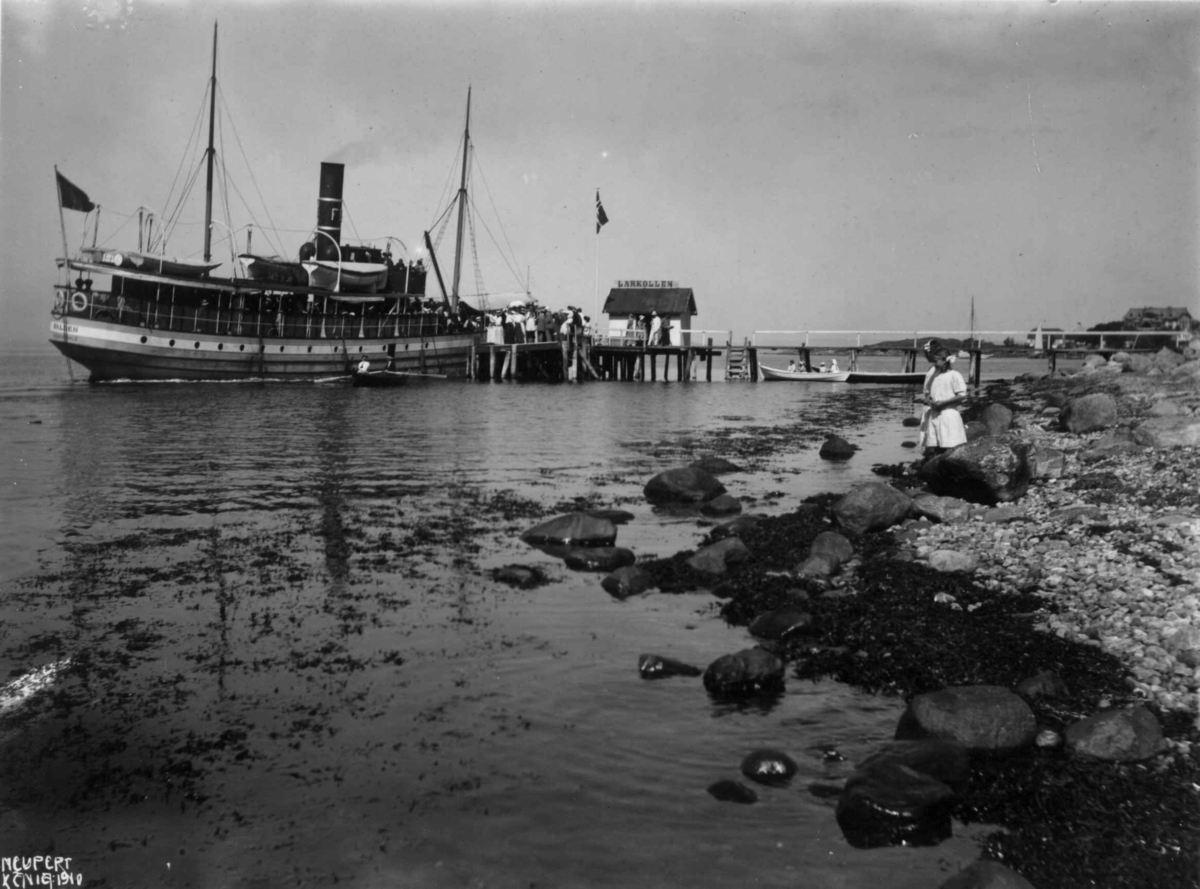 Dampbåten "Halden" 1910. Larkollen - Rygge - Østfold. 
Brygge. Robåter. Passajerer. Et barn leker i fjæra. Foto Neupert. Platen er dat. aug. 1910.