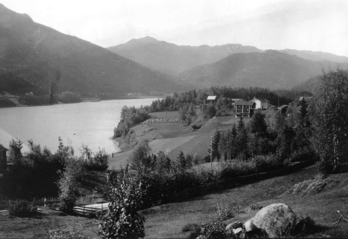 Kravik, Nore, Nore og Uvdal. 1930. Oversiktsbilde. Utsikt mot gården omgitt av jorder og skog. Vann. Fjell i bakgrunnen.