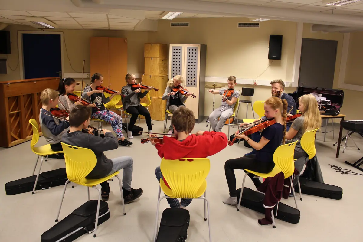 Bilde av barn som sitter i ring og spiller fele. 