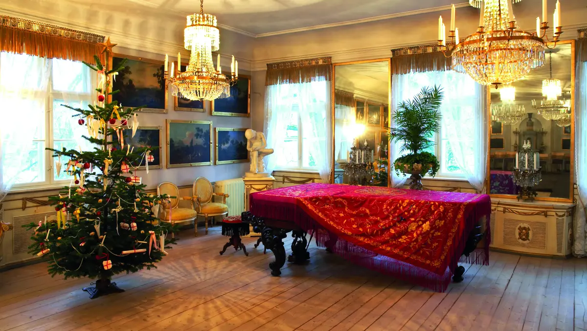 Et flygel med rød duk og et pyntet juletre i en av stuene på Bogstad gård. 