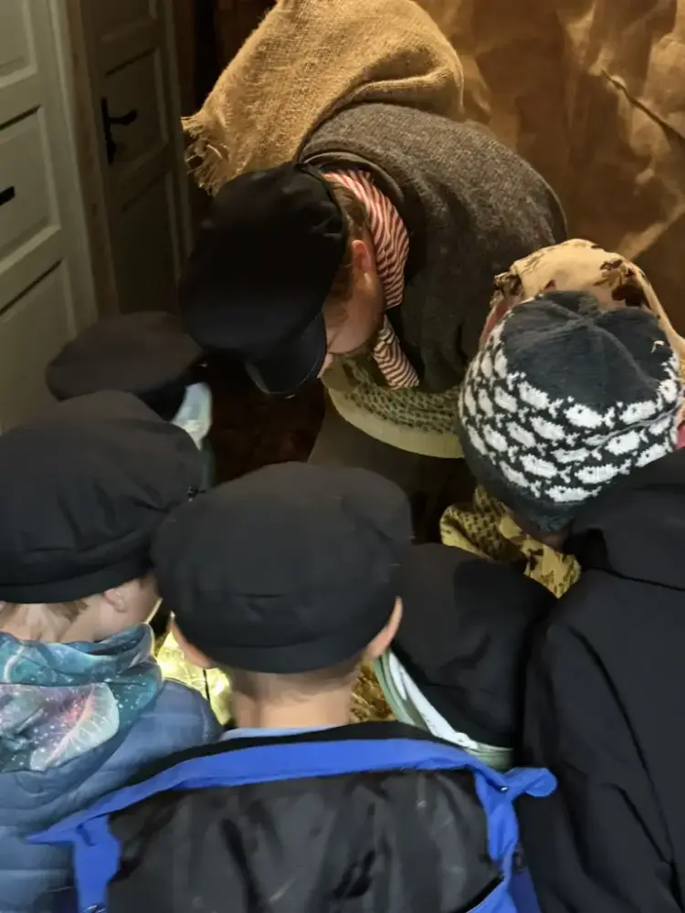 Vi ser flere barn og en fisker bøyd over et brev som ligger på tønnen