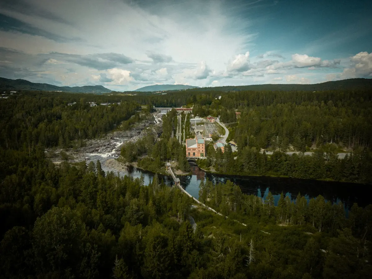 Bilde av Labroområdet på avstand. Vi ser kraftstasjonen, rørgatene, tømmerrenna og elva.