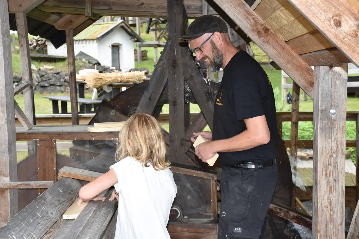 Bilde av musemsvert og barn som bruker saga drevet av vannkraft på Labro.