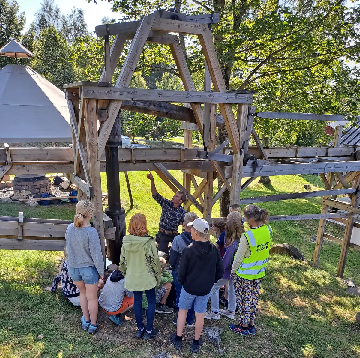 Bilde av skoleelever og museumsvert som viser fram gruvepumpa på Labro. 