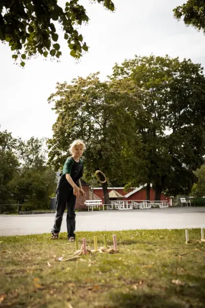 Bilde av et barn som leiker med ringspill på museets område.