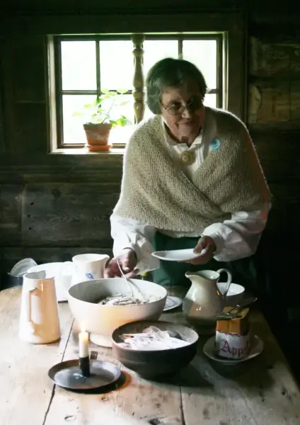 På bildet ser vi en av venneforeningens medlemmer servere tradisjonsmat.