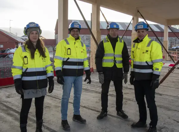 Representanter for entreprenør og byggeprosjekt, ikledd gule arbeidsjakker og hjelm.