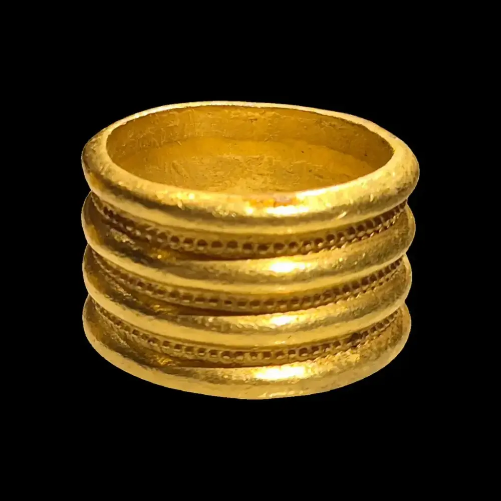 Nærbilde av en gullring funnet i en av gravhaugene våre. Ringen er bred og massiv