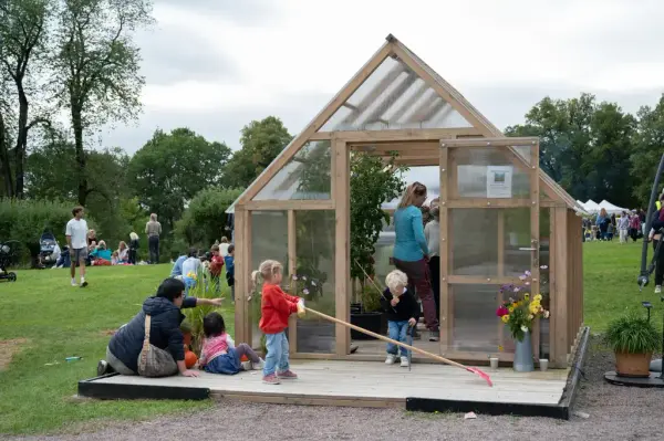 Barn og voksne i og utenfor et drivhus. 