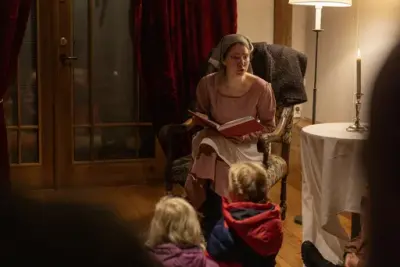 En kvinne i kostyme leser for barna. 