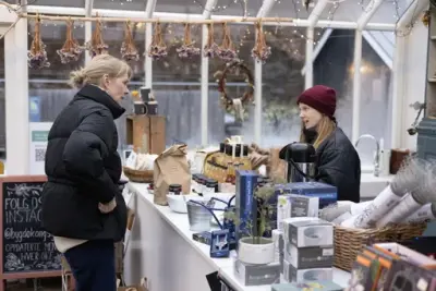 En dame handler i gårdsbutikken på Gartneriet. 