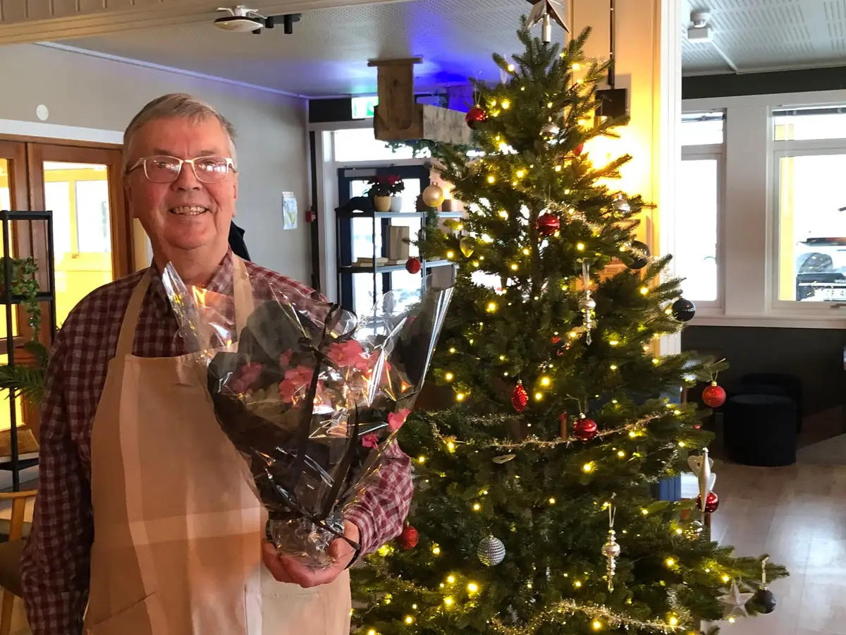 Mann ved siden av eit juletre som holder i en bukett