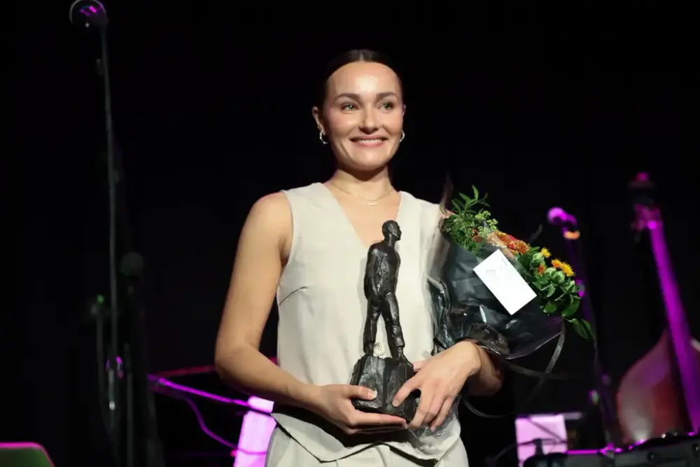 Smilande prisvinnar med blomar og statuett