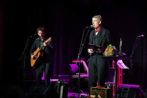 To personar på mørk scene som syng og spelar.