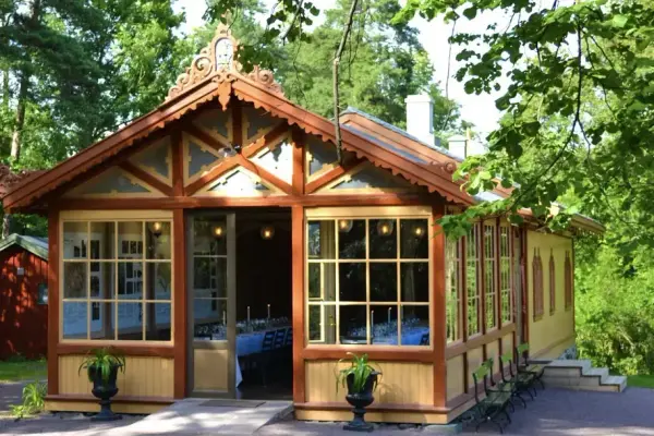 Sæterhytten ved Bygdø Kongsgård sett utenfra, grønt løv og åpne dører.