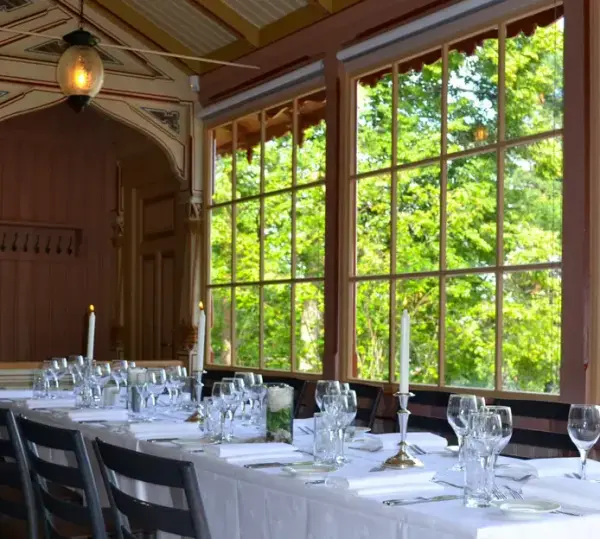 Sæterhytten ved Bygdø Kongsgård sett innenfra, et dekket bord med hvit duk og lys. 