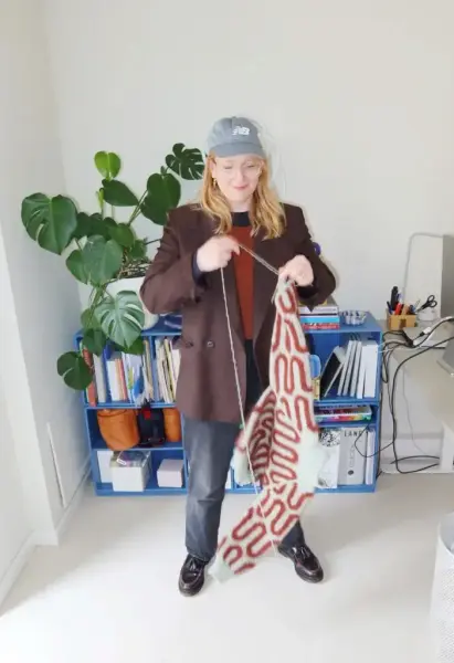 Strikkedesigner Mie Firring holder opp et strikketøy 