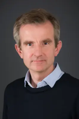 Portrett av mann med blond hår og mørk genser.