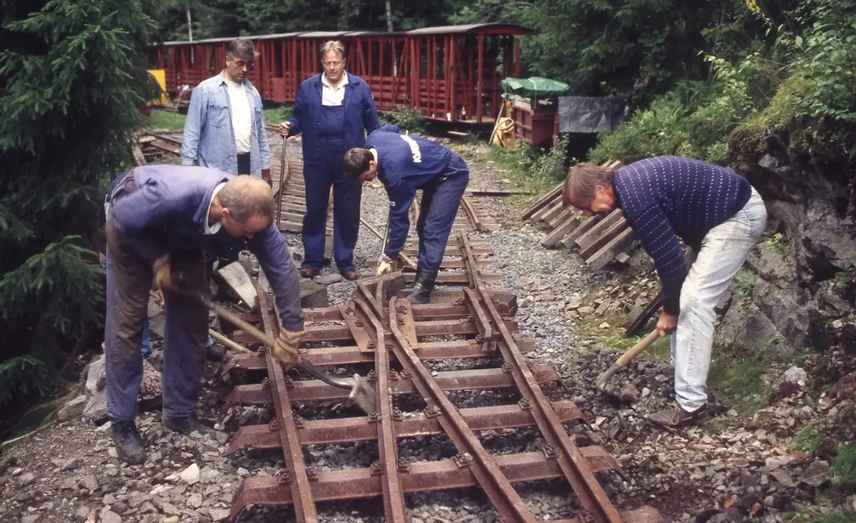 Fem menn i blå klær arbeider på en skinnegang.