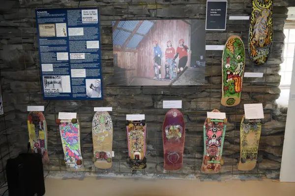 Flere skateboard står oppstilt på en vegg, med infoskiler over hvert skateboard