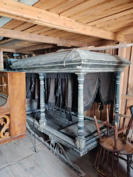 En stor sort begravelsesvogn med støv står lagret med andre tre-gjenstander