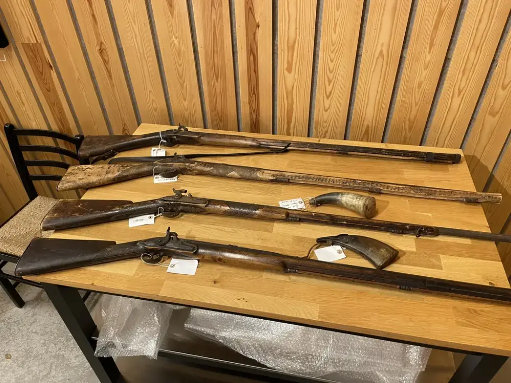 Fire gevær ligger vedsiden av hverandre på et bord 