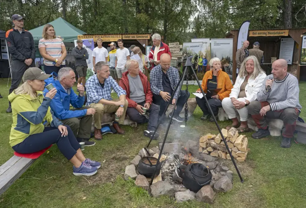 Gruppe mennesker samlet rundt bål under utendørs arrangement.
