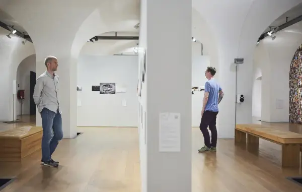 To menn ser på bilder i utstilling