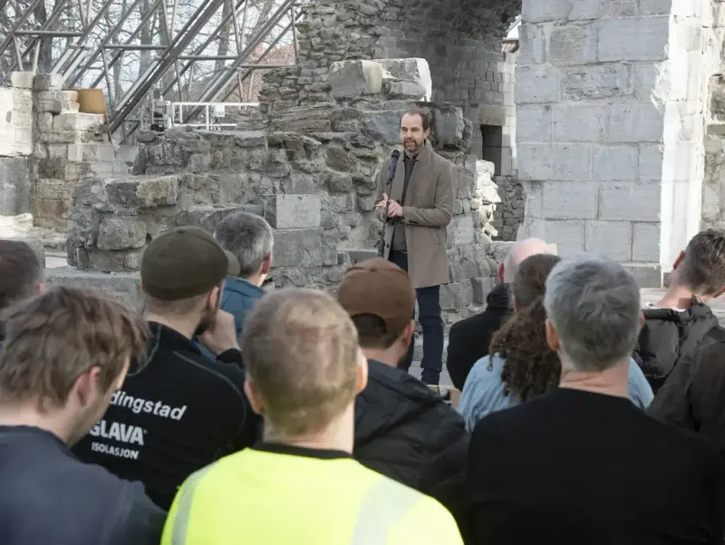 Mann i ullfrakk holder tale i Hamardomen for arbeiderne og andre inviterte til kranselag.