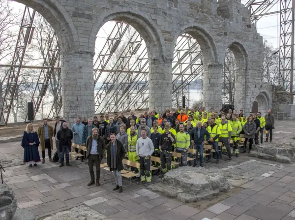 Alle involverte fra arbeidere og byggherre står samlet foran kirkeruinen fra middelalderen i forbindelse med kranselag.