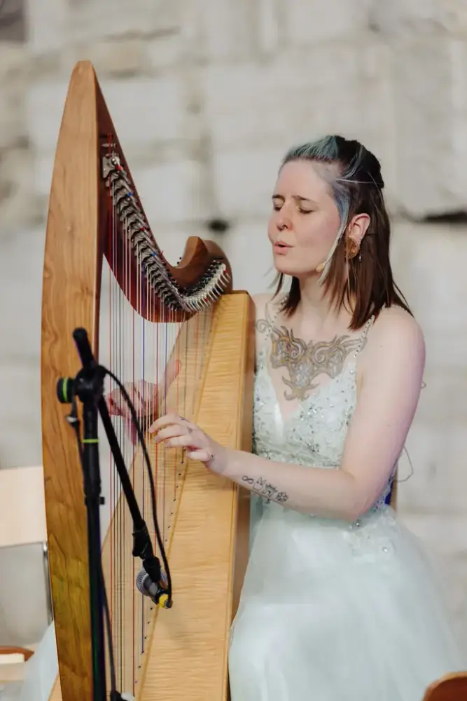 Ung kvinne i tyllkjole spiller harpe i domkirkeruinen.