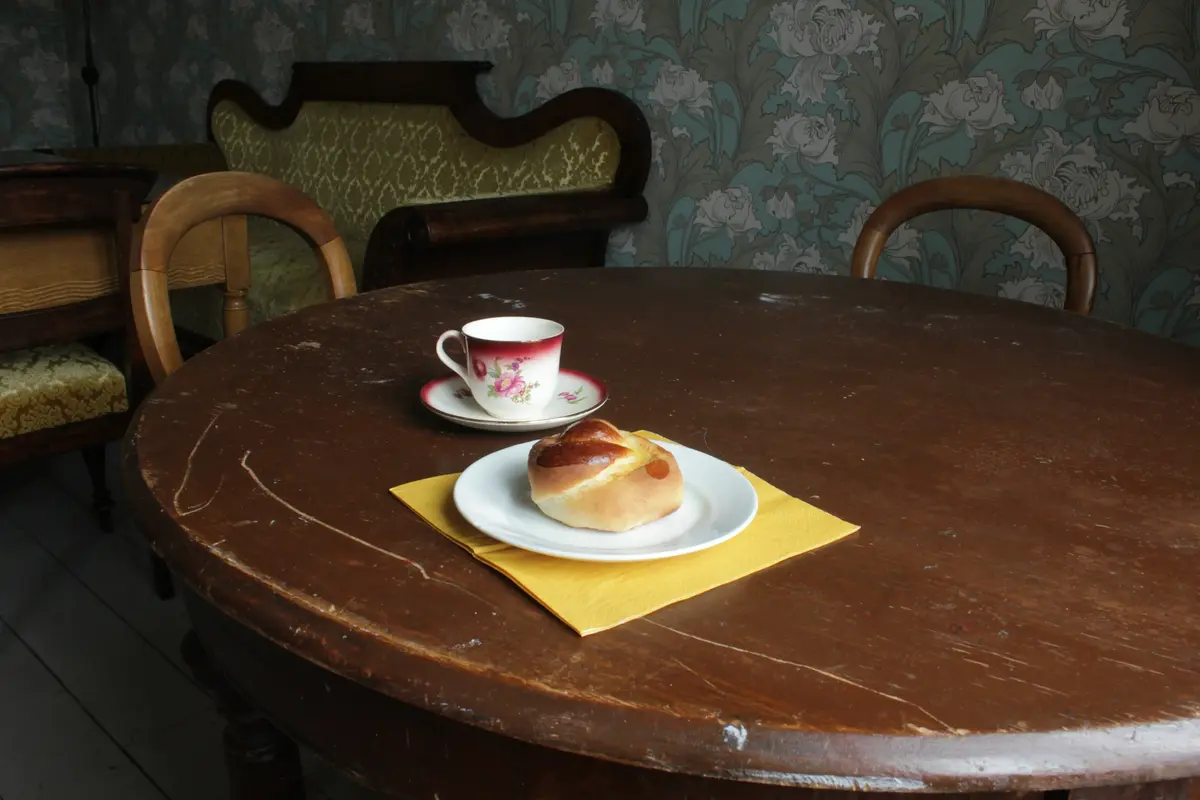 Rundt trebord med totenkringle på en asjett og en eldre kaffekopp på skål. 