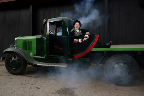 Kvinne i bunad sitter i en gammel lastebil med røykeffekter under påskekrimmen på Norsk Folkemuseum.
