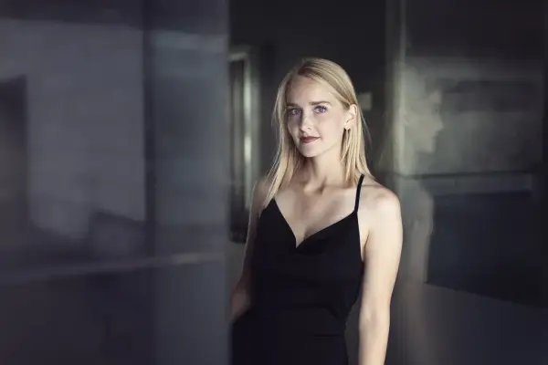 Portrett av mezzosopran Christina Herrestahl i sort kjole, stående innendørs i dempet lys før påskekonsert på Norsk Folkemuseum.