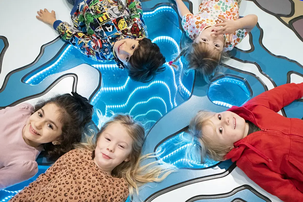 5 barn i utställningen Småfolk som ligger på blått golv