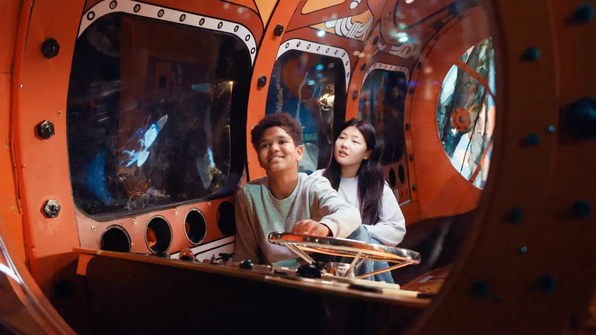 Two children inside a submarine installation in the Explore the Ocean exhibition at the Norwegian Maritime Museum.