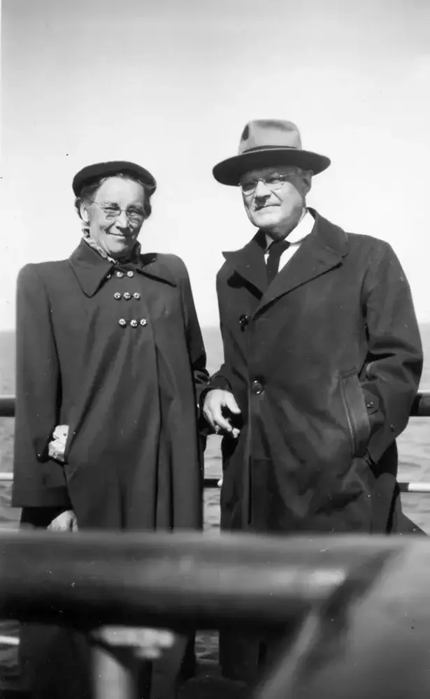 En mann og en kvinne lener seg mot relingen på en båt. Vann i bakgrunn.