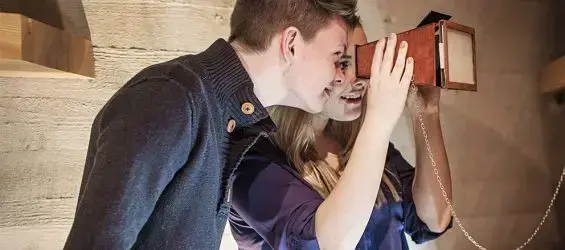 Ein gut og ei jente ser i eit stereoskop i utstillinga i Aasentunet