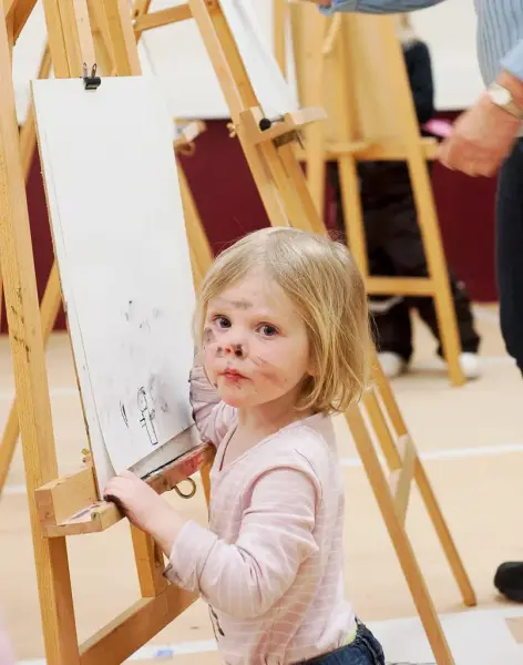 Liten flicka med färg i ansiktet som står vid ett golvstaffli