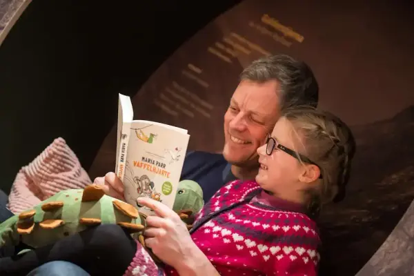 mann les frå boka Vaffelhjarte til jente i utstillinga i Vinjesenteret