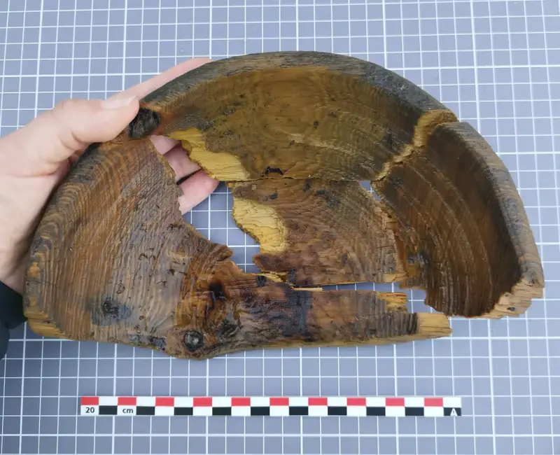 Hånd holder fragmentert dreid trebolle, funnet i Bjørvika.