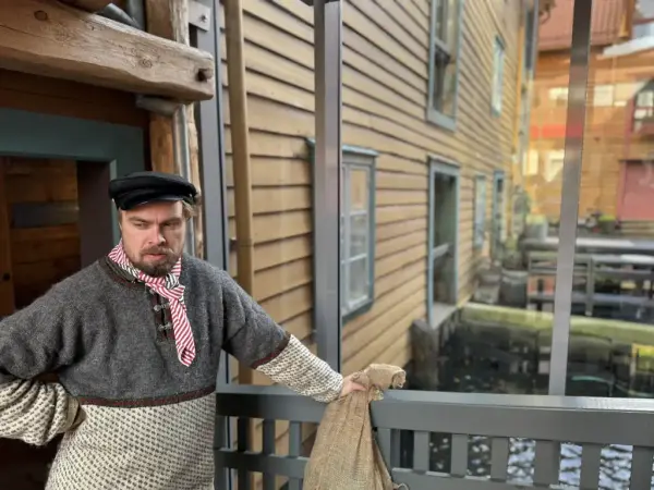 Her ser vi en ansatt ved broen over hope eller kanalen som er mellom to av sjøbodene. 