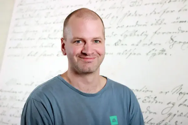 Portrettfoto av Stein Arnold Hevrøy framom ein skriftvegg i utstillinga i Aasentunet