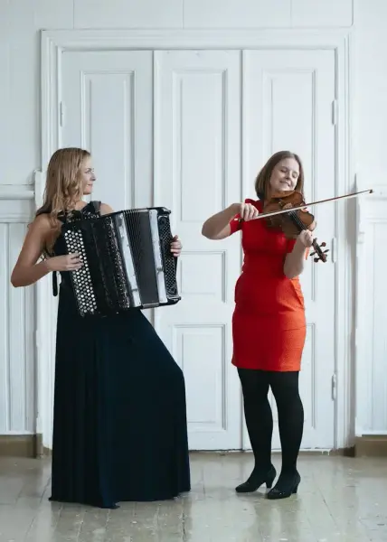 Kristina Bjørdal Farsta med svart kjole og trekkspel og Jorun Marie Kvernberg med raud kjole og fele