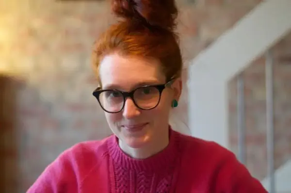 Karen Frøsland Nystøyl i rosa genser sitjande framom ei trapp