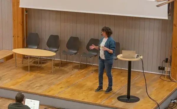 Kvinne med jakke formidler fra en scene 